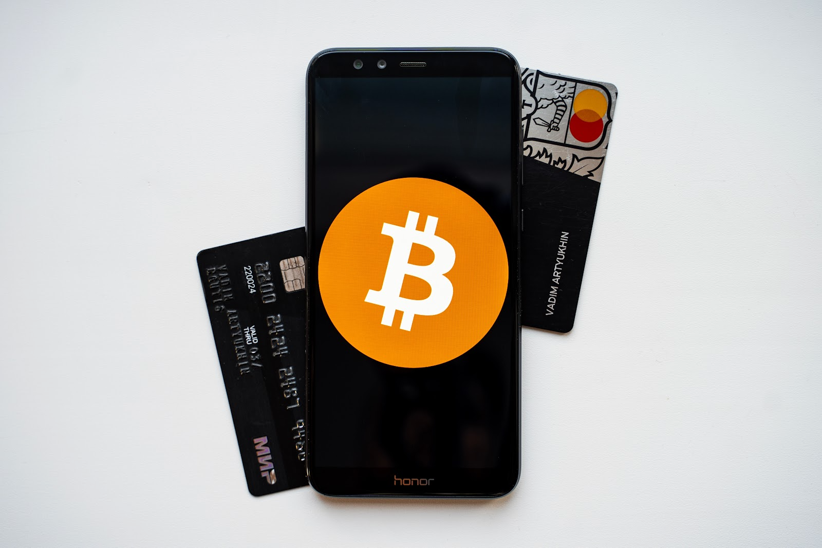 A mobile phone with the BTC logo on top of a few credit cards